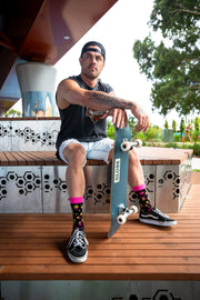 Male model poses with skateboard wearing bold and colourful funky Beer and BBQ Festival socks.