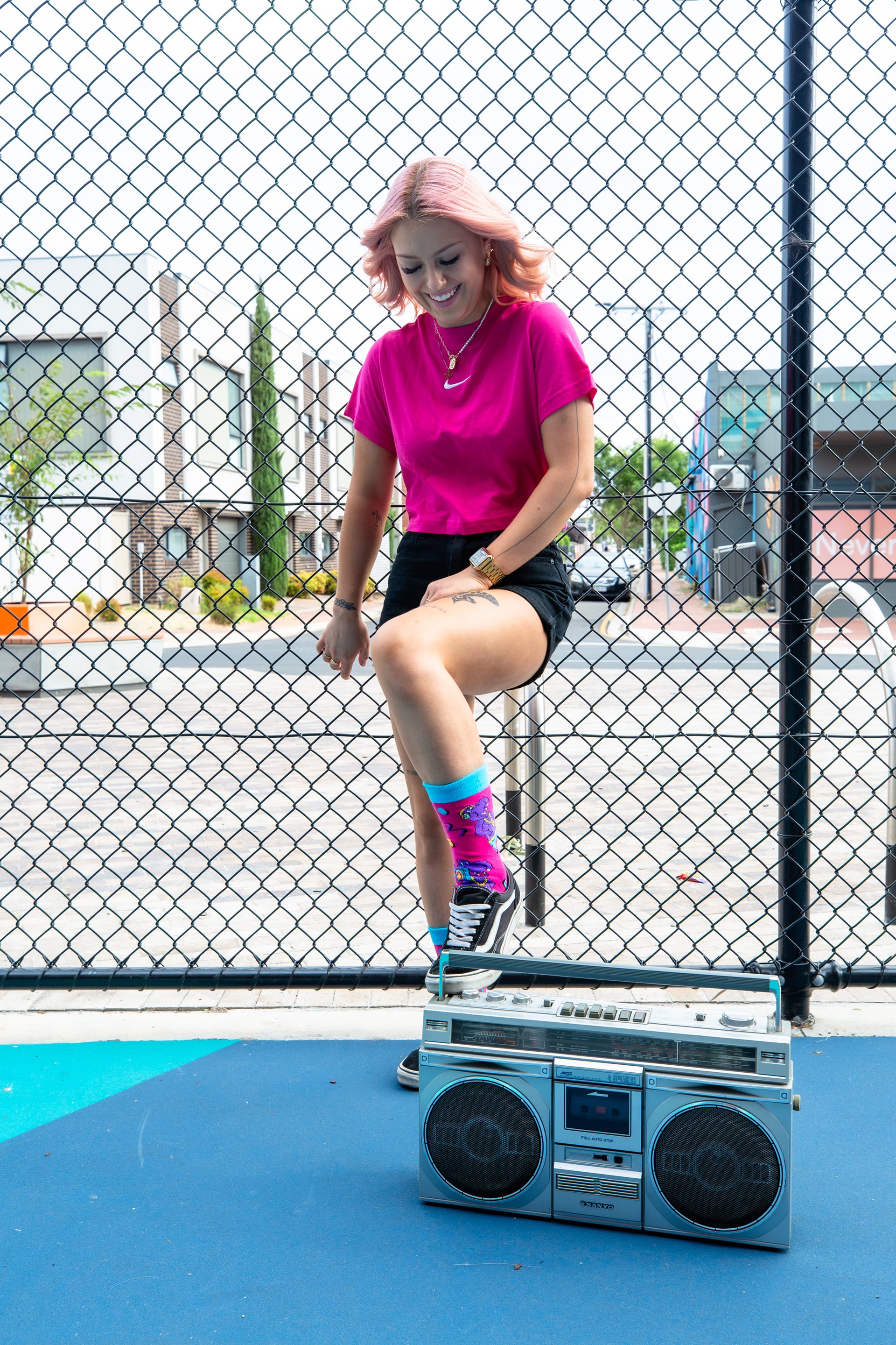 Young girl posing with retro 90's boombox wearing bright pink hip hop funky novelty hippo socks.